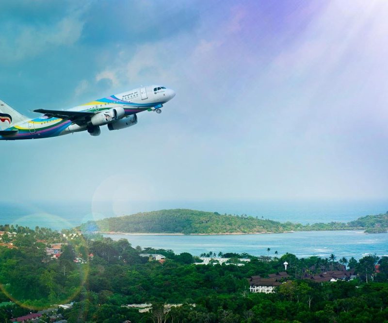 Airplane soaring over Koh Samui island, Thailand, showcasing a vibrant tropical landscape in daylight.