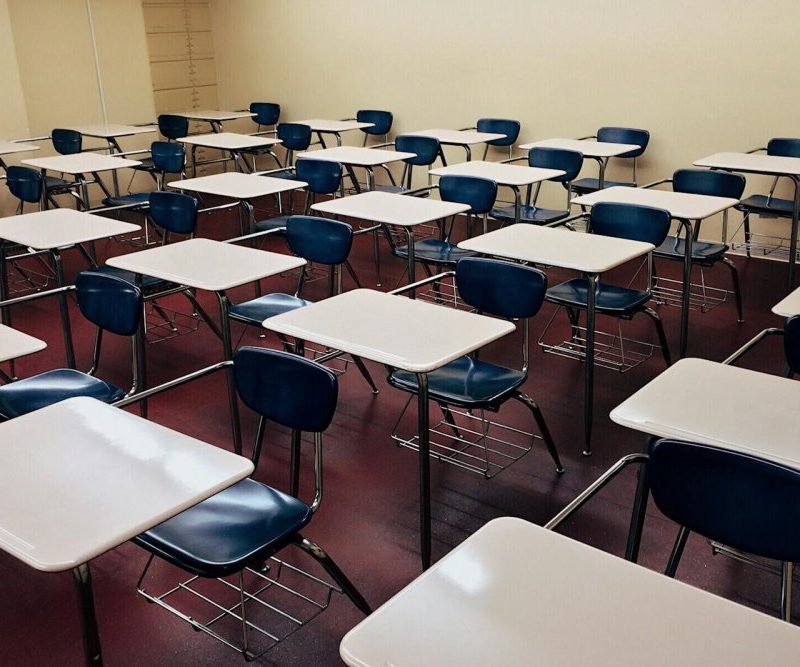 An indoor view of a modern, clean classroom with rows of empty desks and chairs.