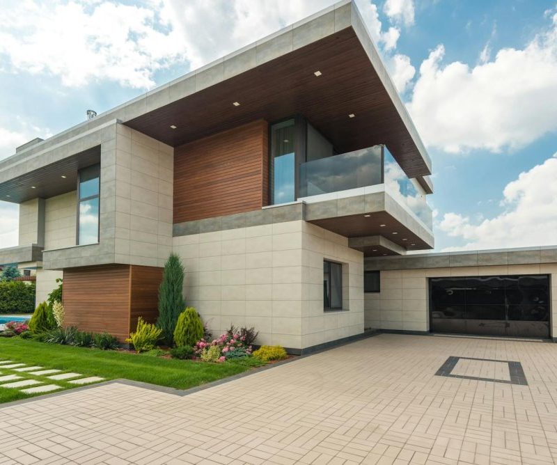 Contemporary luxury house with a sleek design, lush garden, and blue sky.