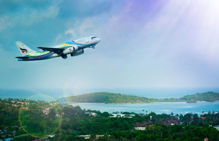 Airplane soaring over Koh Samui island, Thailand, showcasing a vibrant tropical landscape in daylight.