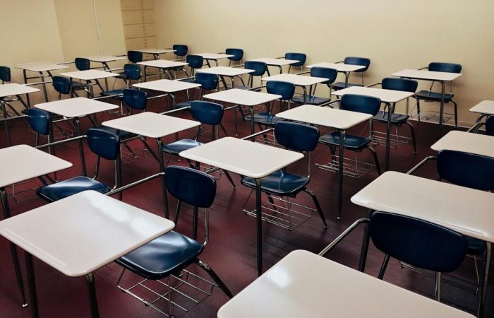 An indoor view of a modern, clean classroom with rows of empty desks and chairs.